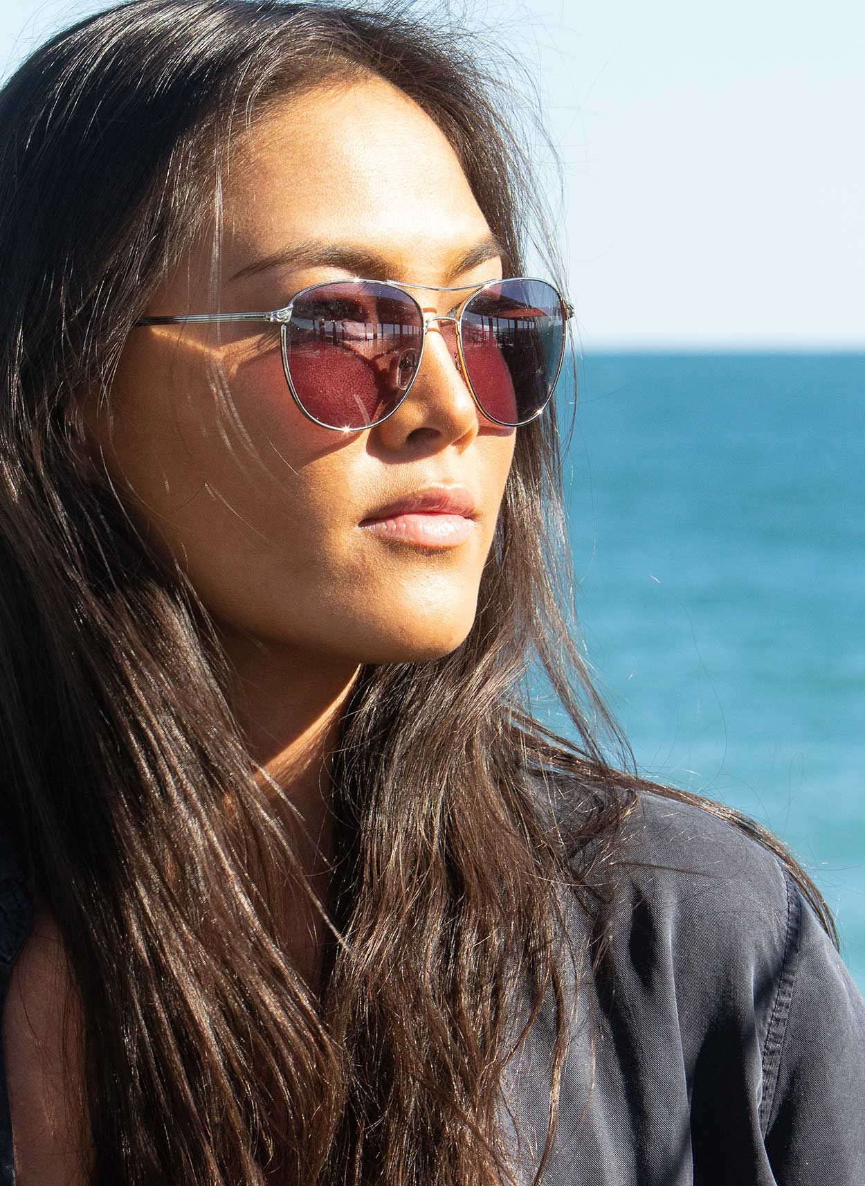 Woman wearing sunglasses with a clear blue sky and ocean background